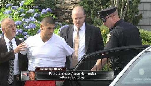 In this image taken from video, police escort Aaron Hernandez from his home in handcuffs in Attleboro, Mass., Wednesday, June 26, 2013. Hernandez was taken from his home more than a week after a Boston semi-pro football player was found dead in an industrial park a mile from Hernandez's house. (AP Photo/ESPN)