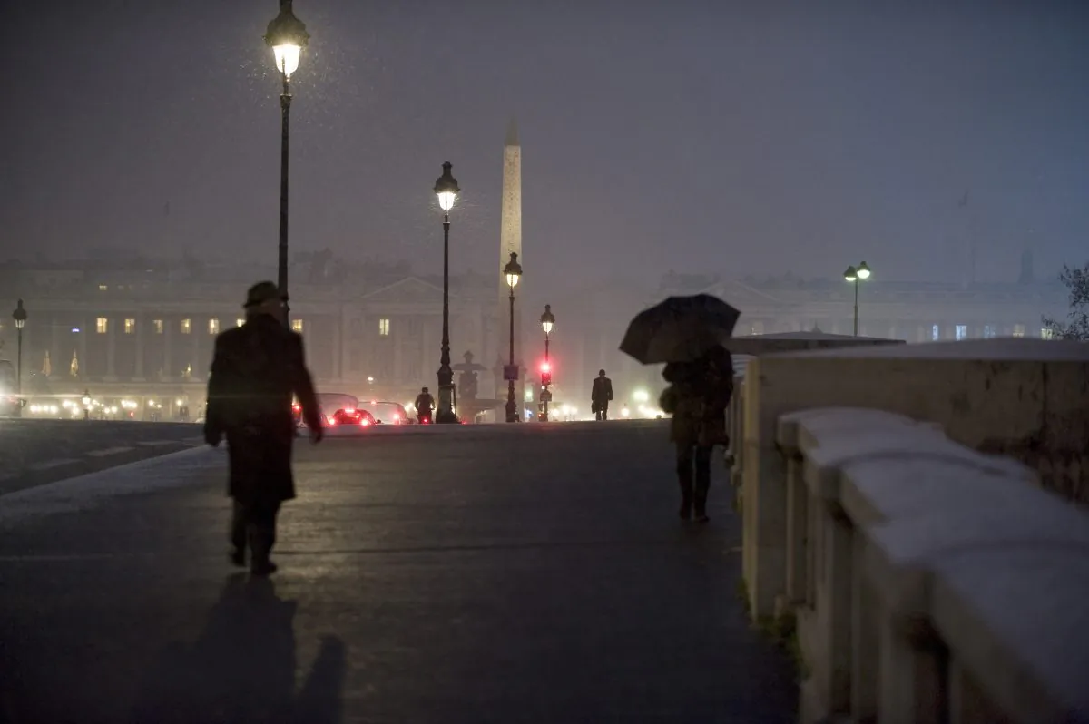 People walk on the snow-covered Pont de la Concorde in Paris on December 17, 2009. Many have witnessed public streetlights that mysteriously go dark as someone passes below.  Over the years, as these individuals have begun to share their experiences, this phenomenon has come to be known as Street Light Interference (SLI). (Fred Dufour/AFP/Getty Images)


