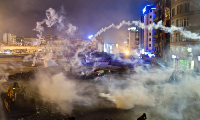Taksim Square is flooded by tear gas as clashes between protesters and riot police continue into the night in Istanbul Tuesday, June 11, 2013. Hundreds of police in riot gear forced through barricades in the square early Tuesday, pushing many of the protesters who had occupied the square for more than a week into a nearby park. (AP Photo/Vadim Ghirda)