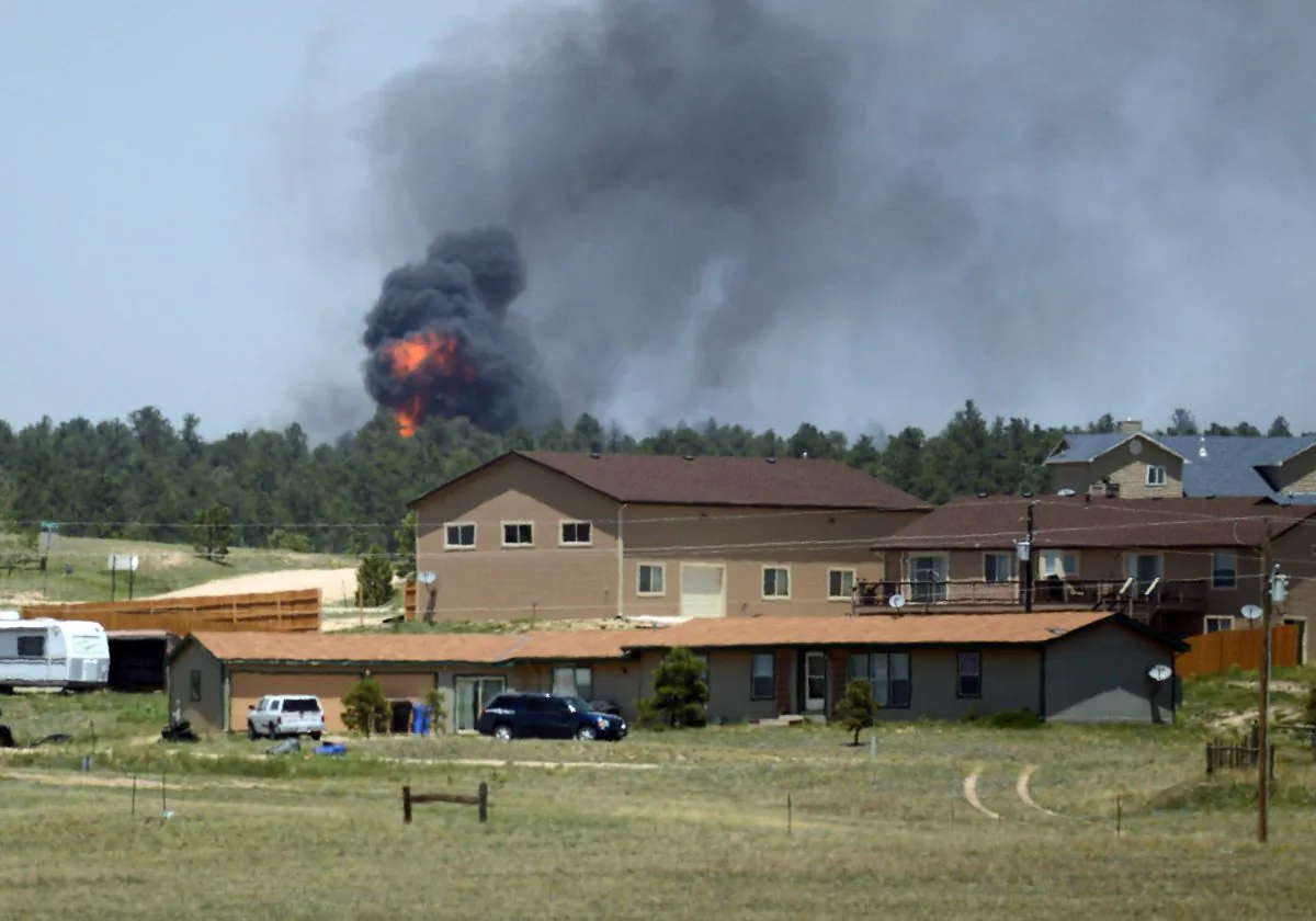Fire erupts behind a home as the Black Forest Fire burns out of control for a second straight day near Colorado Springs, Colo. on Wednesday, June 12, 2013. The fire has consumed at least 7500-8000 acres. It has destroyed 92 homes and damaged others. The erratic fire has forced the evacuation of thousands of people in the Black Forest and portions of Colorado Springs. (AP Photo/Bryan Oller)