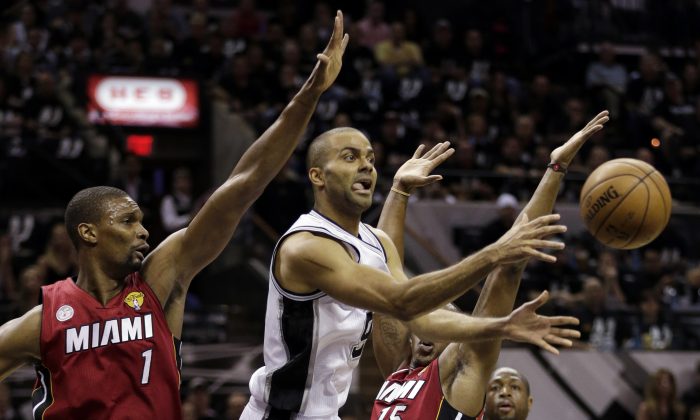 San Antonio Spurs' Tony Parker (9) passes the ball against Miami Heat's Chris Bosh (1) and Mario Chalmers (15) during the first half at Game 3 of the NBA Finals basketball series, Tuesday, June 11, 2013, in San Antonio. (AP Photo/Eric Gay)