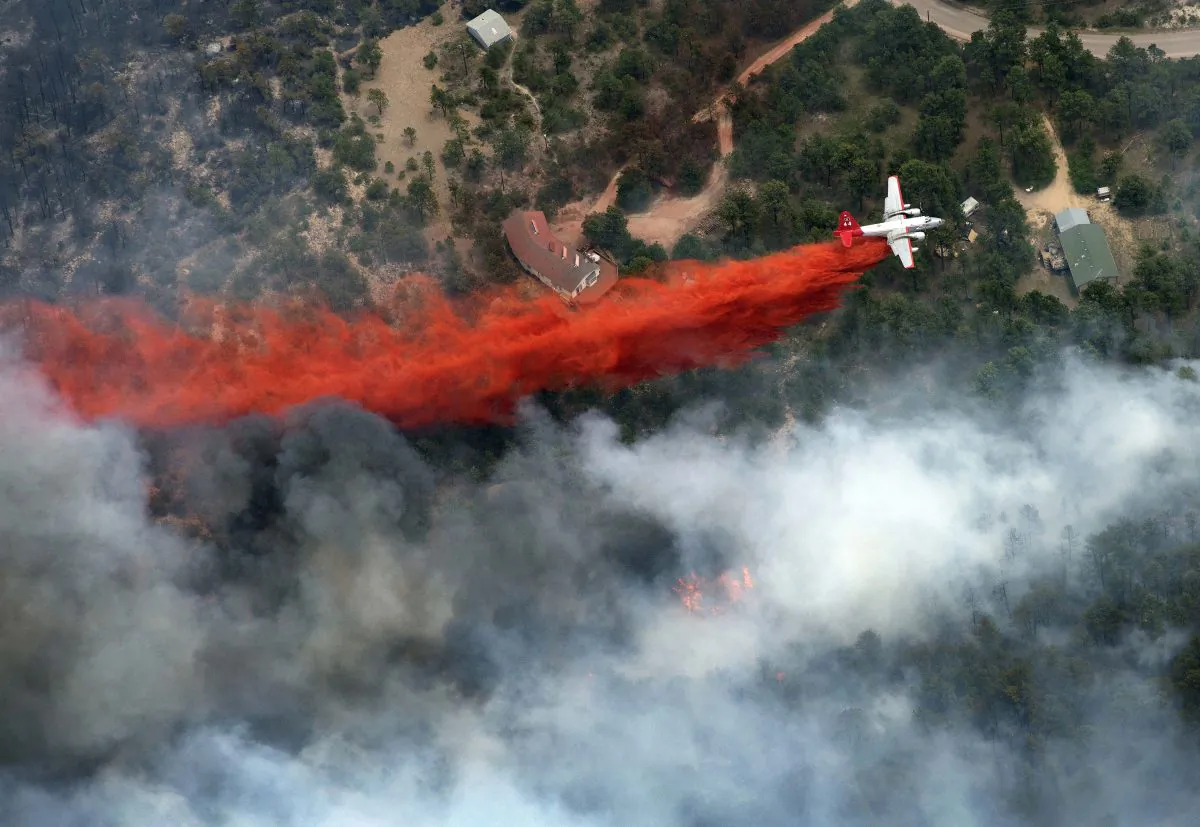 An aircraft lays down a line of fire retardant between a wildfire and homes in the dry, densely wooded Black Forest area northeast of Colorado Springs, Colo., Thursday, June 13, 2013. The fire is being called the most destructive in Colorado history. (AP Photo/John Wark)