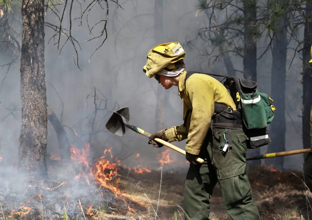 An AmeriCorps volunteer firefighter assigned to the El Paso County Sheriff's Office, Woodland Fire Crew, helps contain a fire north of Colorado Springs, Colo., on June 13, 2013. (Brennan LinsleyAP Photo)