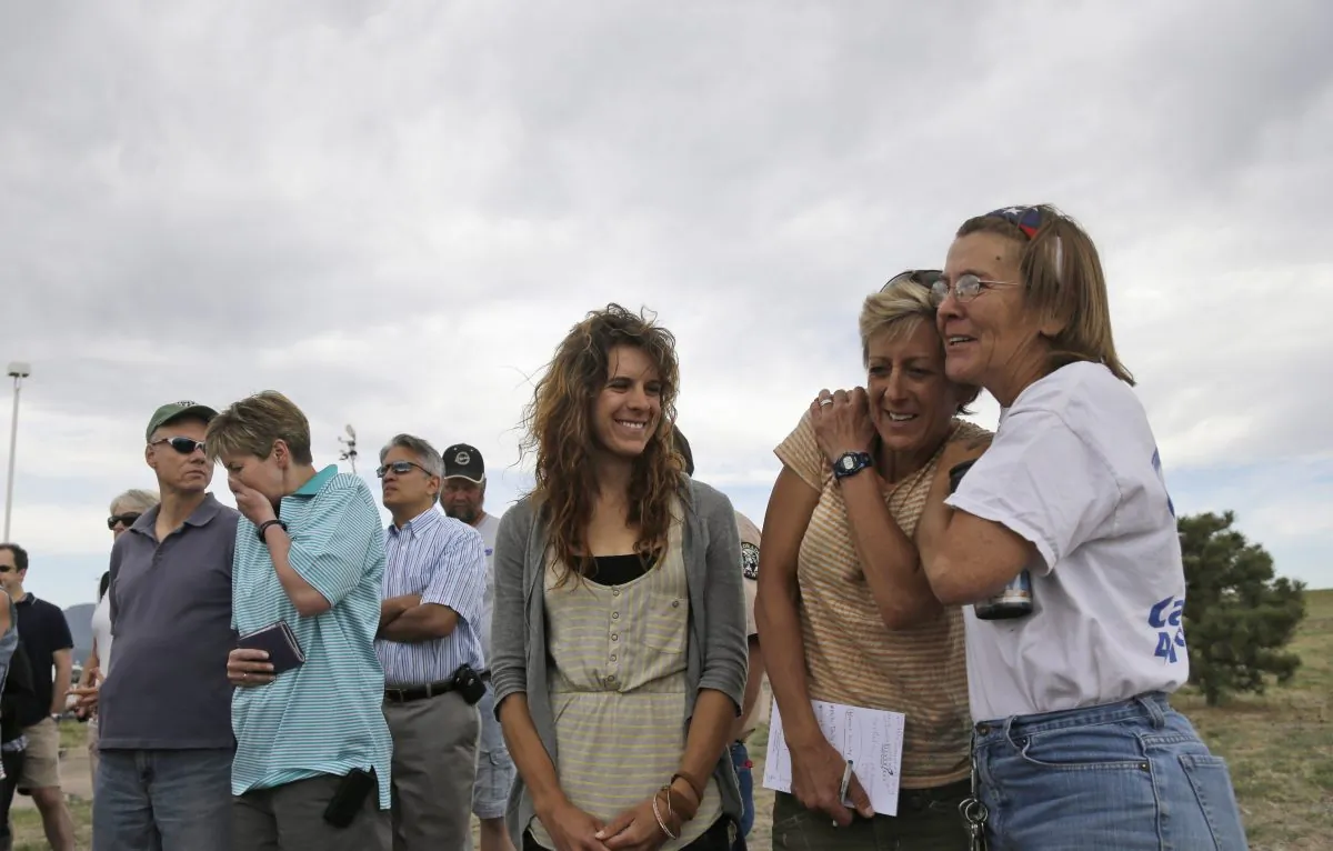 Nancy Bradley, right, a resident of Black Forest, Colo., hugs fellow evacuee Jenny Abernathy, second from right, as Rebecca Abernathy, third from right, Jenny's daughter, watches while listening to an update on the Black Forest Fire in Colorado Springs, Colo., Friday, June 14, 2013. (AP Photo/Marcio Jose Sanchez)