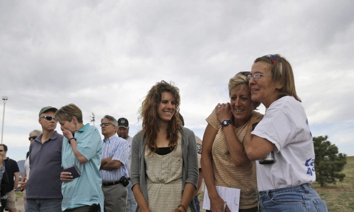 Nancy Bradley, right, a resident of Black Forest, Colo., hugs fellow evacuee Jenny Abernathy, second from right, as Rebecca Abernathy, third from right, Jenny's daughter, watches while listening to an update on the Black Forest Fire in Colorado Springs, Colo., Friday, June 14, 2013. (AP Photo/Marcio Jose Sanchez)