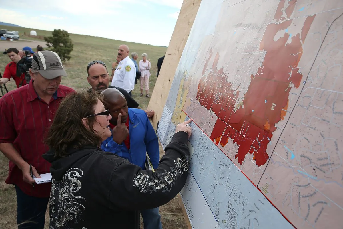 Residents look at a map showing the areas damaged by the Black Forest fire in Colorado Springs, Col., on June 14, 2013. John Bissett, president of the Housing and Building Association of Colorado Springs,  shares his story of personal hardship and professional feats as the fire nears containment on June 19, 2013. (Justin Sullivan/Getty Images) 