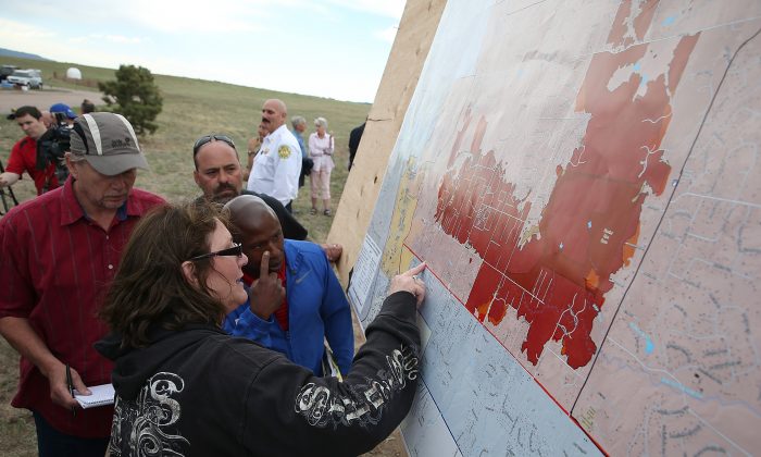 Residents look at a map showing the areas damaged by the Black Forest fire in Colorado Springs, Col., on June 14, 2013. John Bissett, president of the Housing and Building Association of Colorado Springs,  shares his story of personal hardship and professional feats as the fire nears containment on June 19, 2013. (Justin Sullivan/Getty Images) 