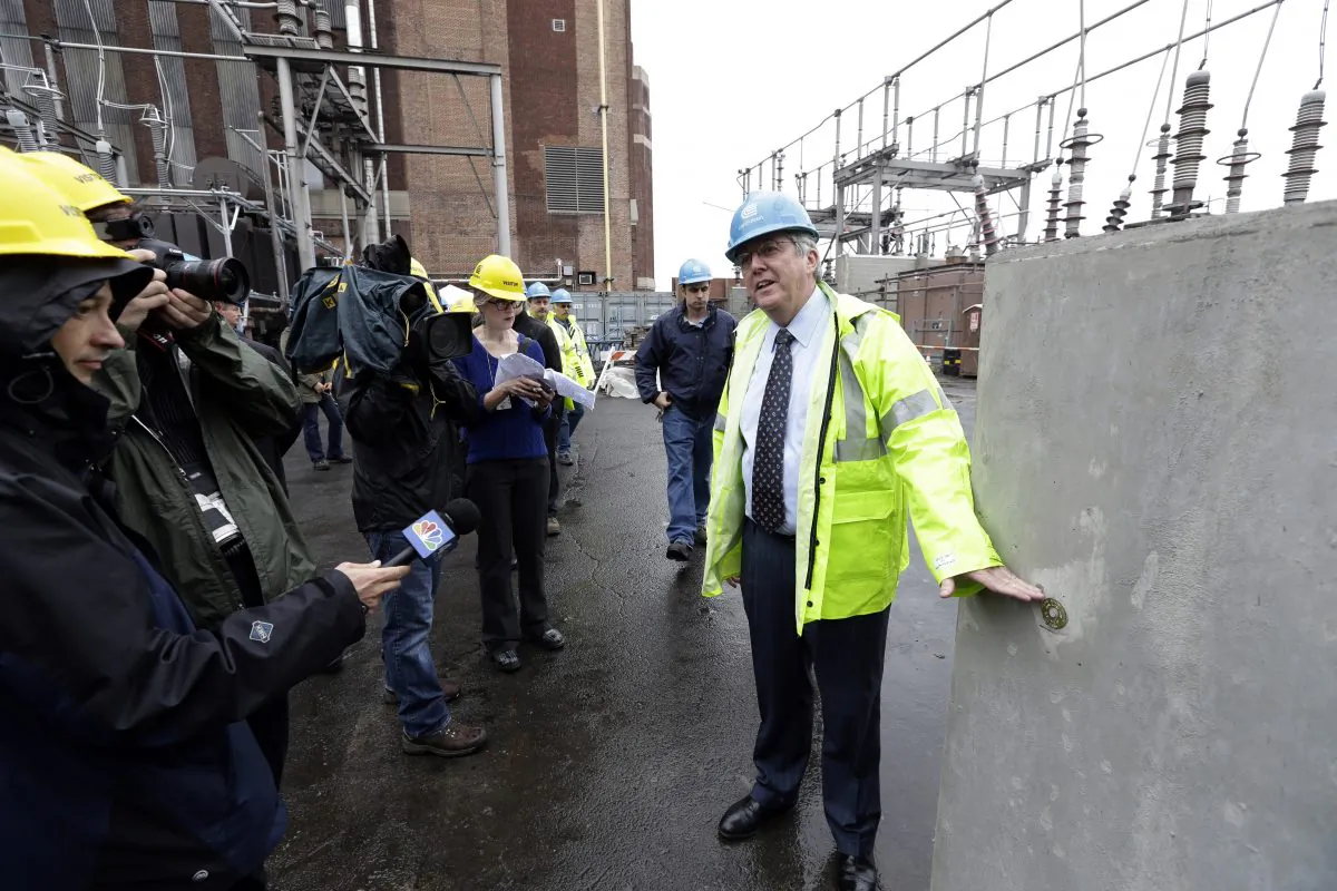 Con Edison’s Chairman and CEO, Kevin Burke, points to where the flood waters reached during Superstorm Sandy on a wall put up to protect a relay house at the Mill Yard substation during a news conference to announce investments made to protect its energy delivery systems from major storms Tuesday, May 28, 2013, in New York. (AP Photo/Frank Franklin II)