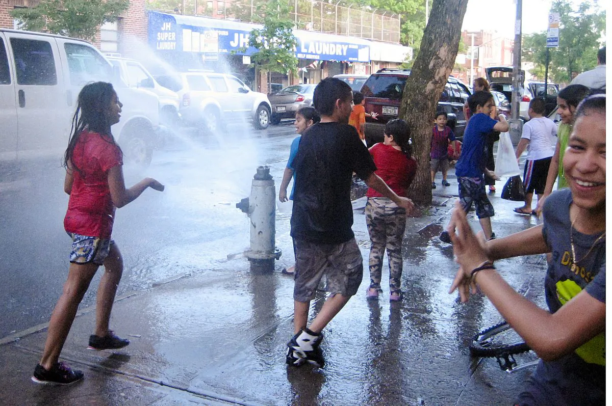 Kids take a break from the heat by playing in the cool water of an open fire hydrant in Jackson Heights, Queens, on June 1. (Joshua Philipp/The Epoch Times)