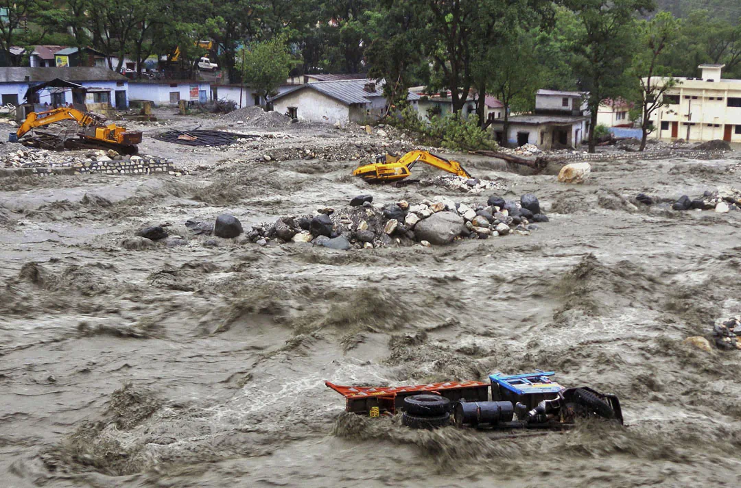 A bulldozer and other vehicles drift in a flooded river in Uttarkashi District, India, Monday, June 17, 2013. Torrential rains and floods washed away buildings and roads. Thousands are feared dead and nearly 60,000 are stranded.  (AP Photo)