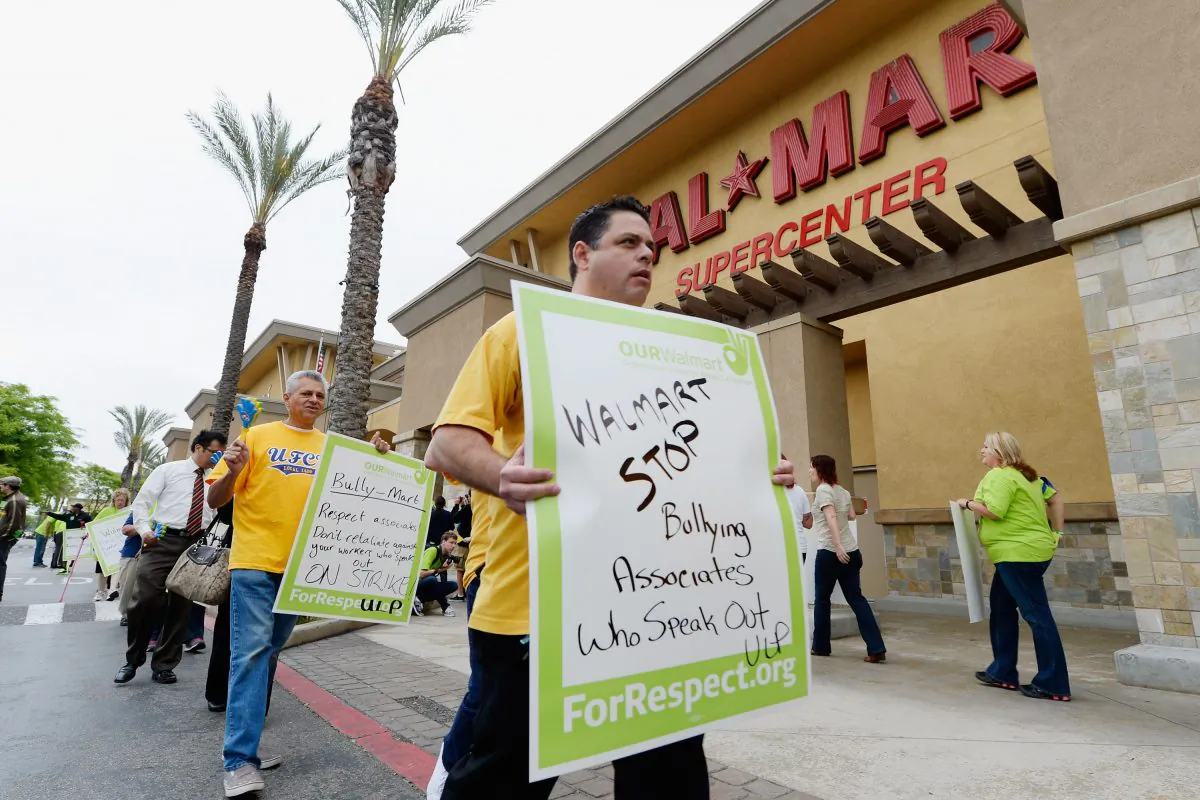 PICO RIVERA, CA - MAY 30: Walmart employees and their supporters walk a picket line to protest Walmart's retaliation against workers who speak out on May 30, 2013 in Pico Rivera, California. Some striking Walmart employees borded a bus to start a 1,500-mile bus journey titled 'Ride for Respect,'' ending at the company's annual meeting at its headquarters in Bentonville, Arkansas. (Kevork Djansezian/Getty Images)