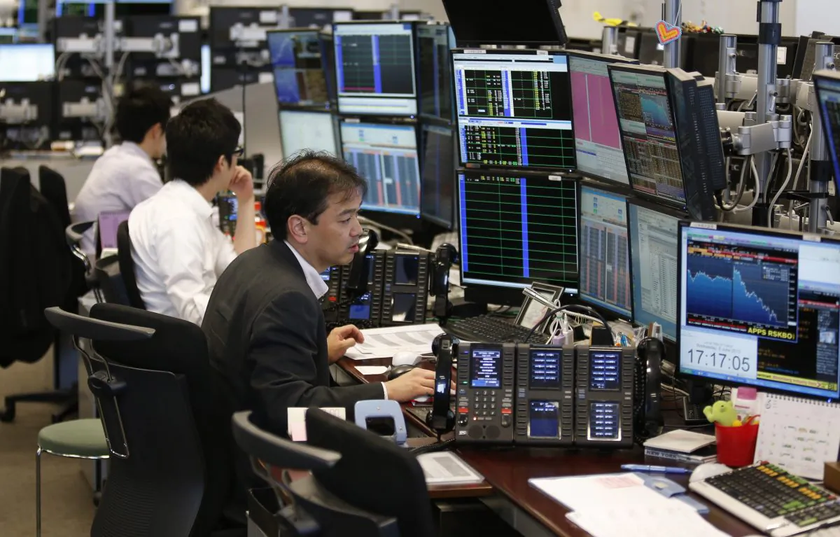 Takashi Yamada (R) a government-bond trader at major brokerage Daiwa Securities Co., monitors screens at his bond trading section in Tokyo on June 5, 2013. Until a couple of months ago, Yamada had one of the most genteel jobs in Japan. Now, his days are so harried he doesn't have time to eat lunch. (Shuji Kajiyama/AP)