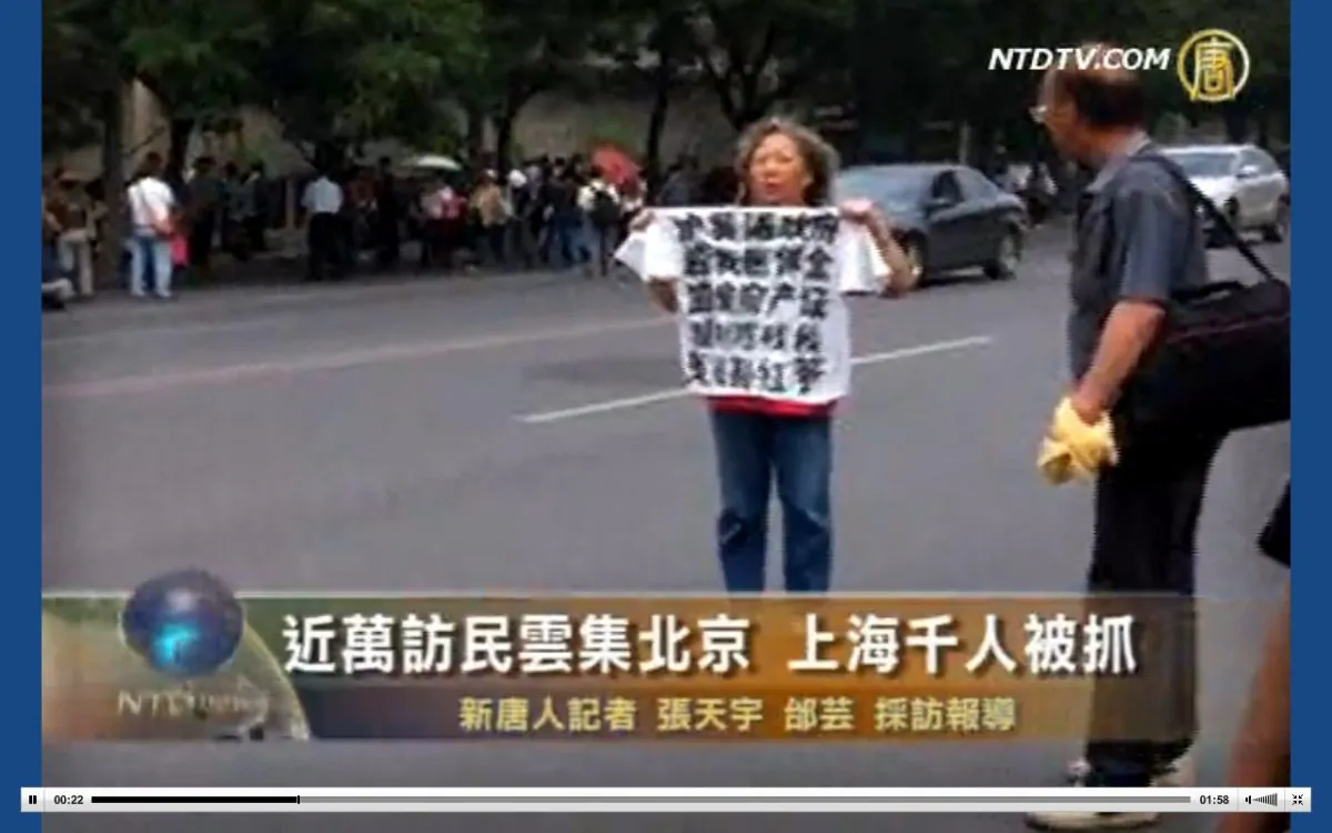 A petitioner holds up a T-shirt with slogans of protest written on it. Thousands of petitioners are reported to have gathered in Beijing on Friday May 31, as the anniversary of June 4 approaches. The authorities packed them into buses. (Screenshot of NTD Television via The Epoch Times)