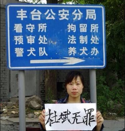 Du Jirong, sister of human rights activist Du Bin, holds up a sign saying “Du Bin is innocent.” outside the Fengtai District Public Security Bureau. (China Human Rights Defenders)