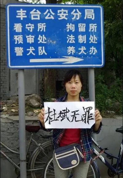 Du Jirong, sister of human rights activist Du Bin, holds up a sign saying “Du Bin is innocent.” outside the Fengtai District Public Security Bureau. (China Human Rights Defenders)