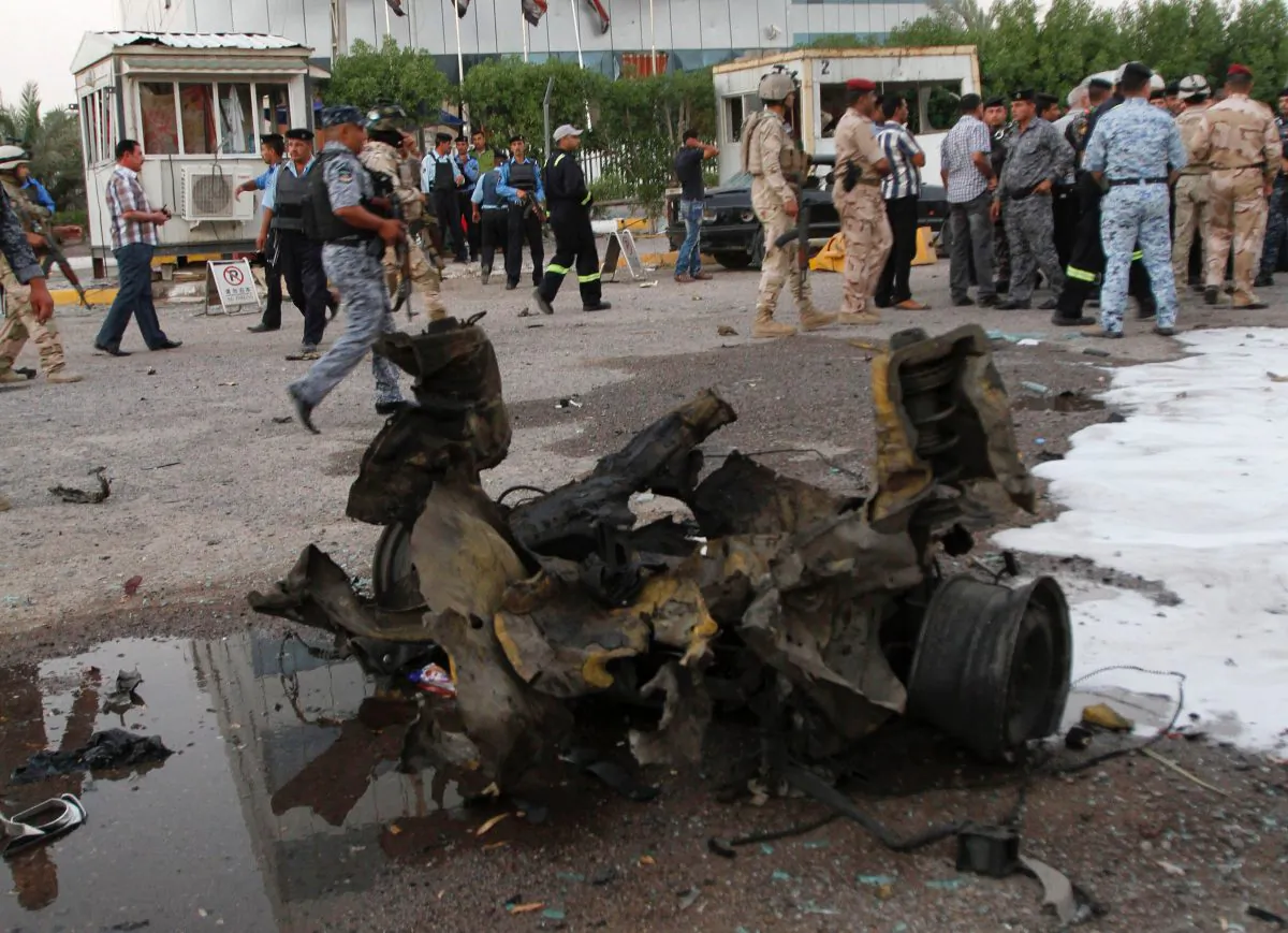 People and security forces inspect the scene of a car bomb attack in Basra, 340 miles (550 kilometers) southeast of Baghdad, Iraq, Tuesday, July 2, 2013. Dozens of people killed and wounded when Insurgents unleashed a new wave of attacks in Iraq on Tuesday as part of a series of attacks in a recent uptick in violence across the country that raised concerns over a return to sectarian bloodshed. (AP Photo/ Nabil al-Jurani)