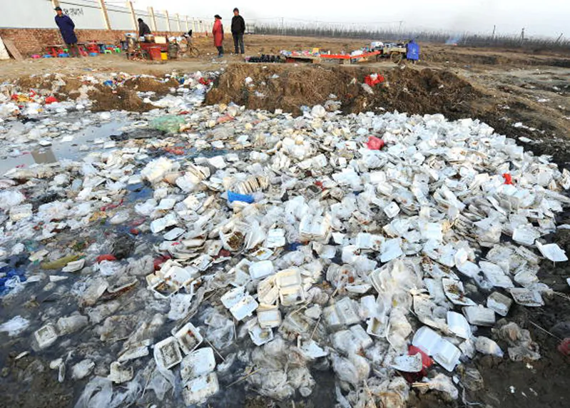 People stand near a landfill strewn with disposable lunch boxes outside a construction site in Hefei, capital city of Anhui Province in China, on Dec. 6, 2009. (Getty Images) 