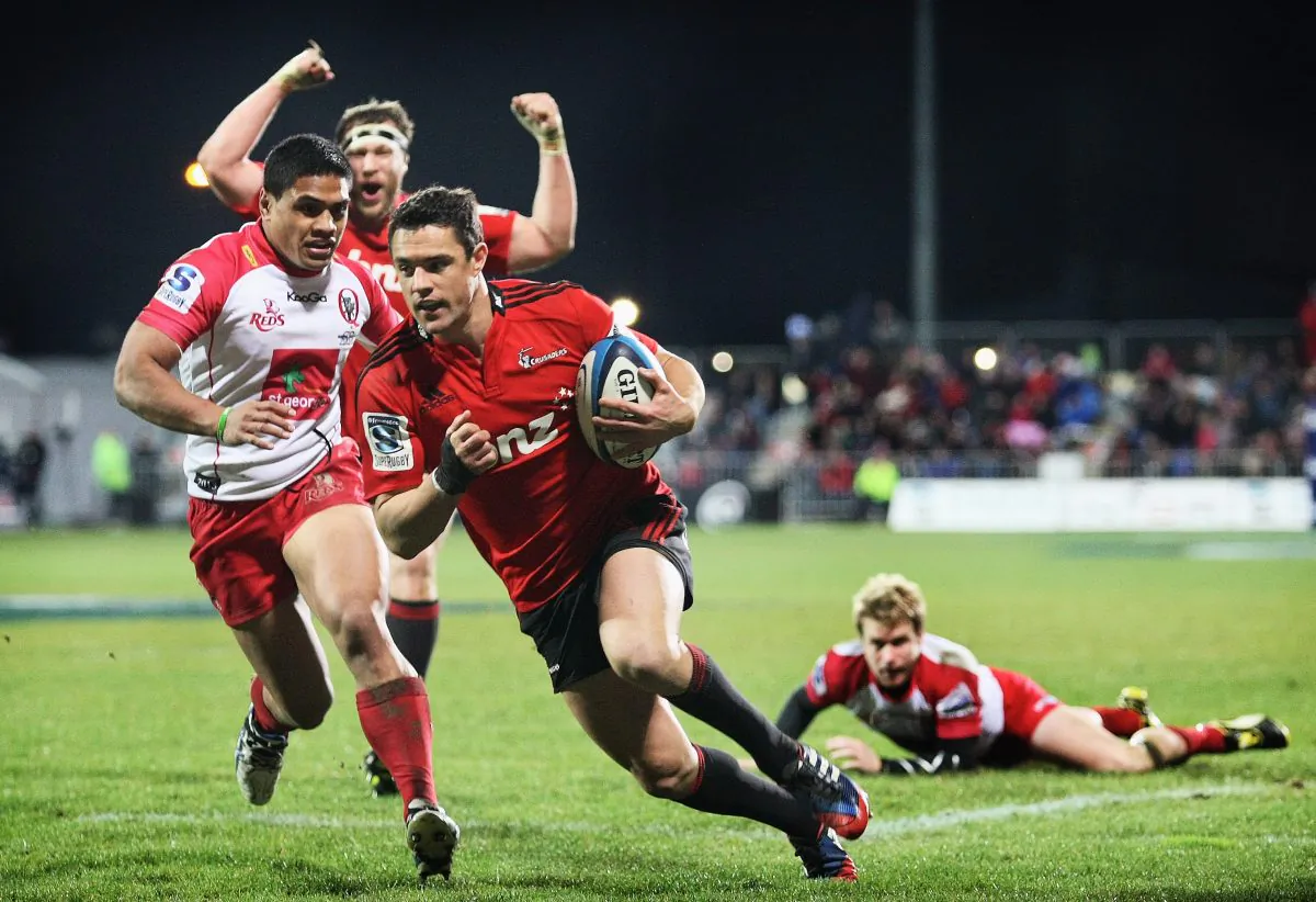 Crusaders star Dan Carter scores against the Reds, as Ben Tapuai pursues in vain and Wyatt Crockett celebrates during their Qualifying Final on Saturday July 20, 2013, in Christchurch, New Zealand. (Joseph Johnson/Getty Images)