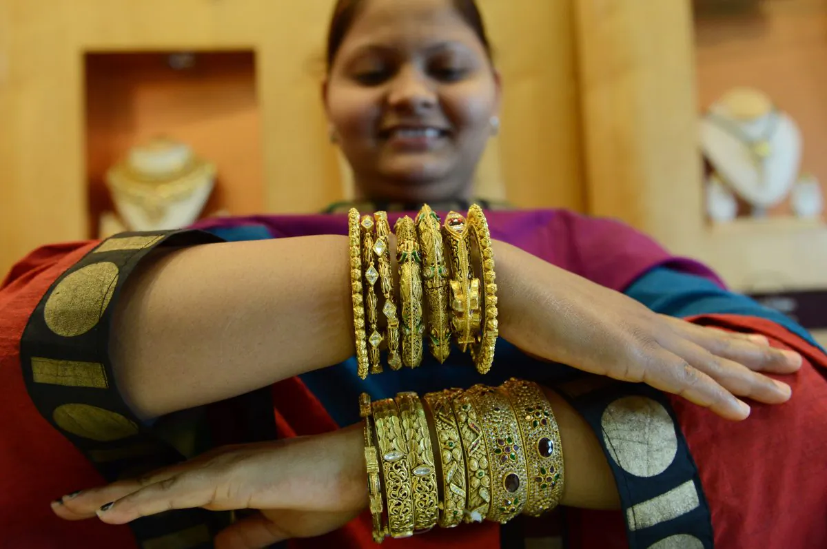 A customer poses with gold jewelry at a store in Ahmedabad, India, May 12. The drop in gold prices is likely to boost gold sales in countries like India and China.
(Sam Panthaky/AFP/Getty Images)