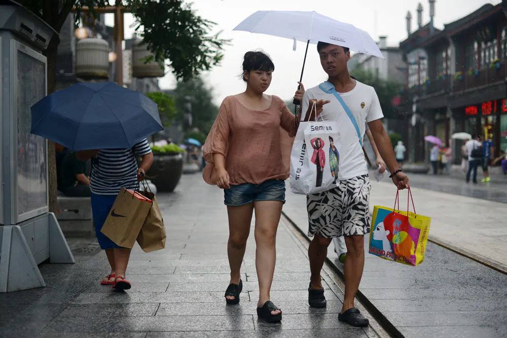 A couple carry shopping bags along a street in Beijing, on July 9, 2013. As Chinese exports slow, domestic consumption in the world’s most populated country is failing to pick up the slack. (Wang Zhao/AFP/Getty Images)