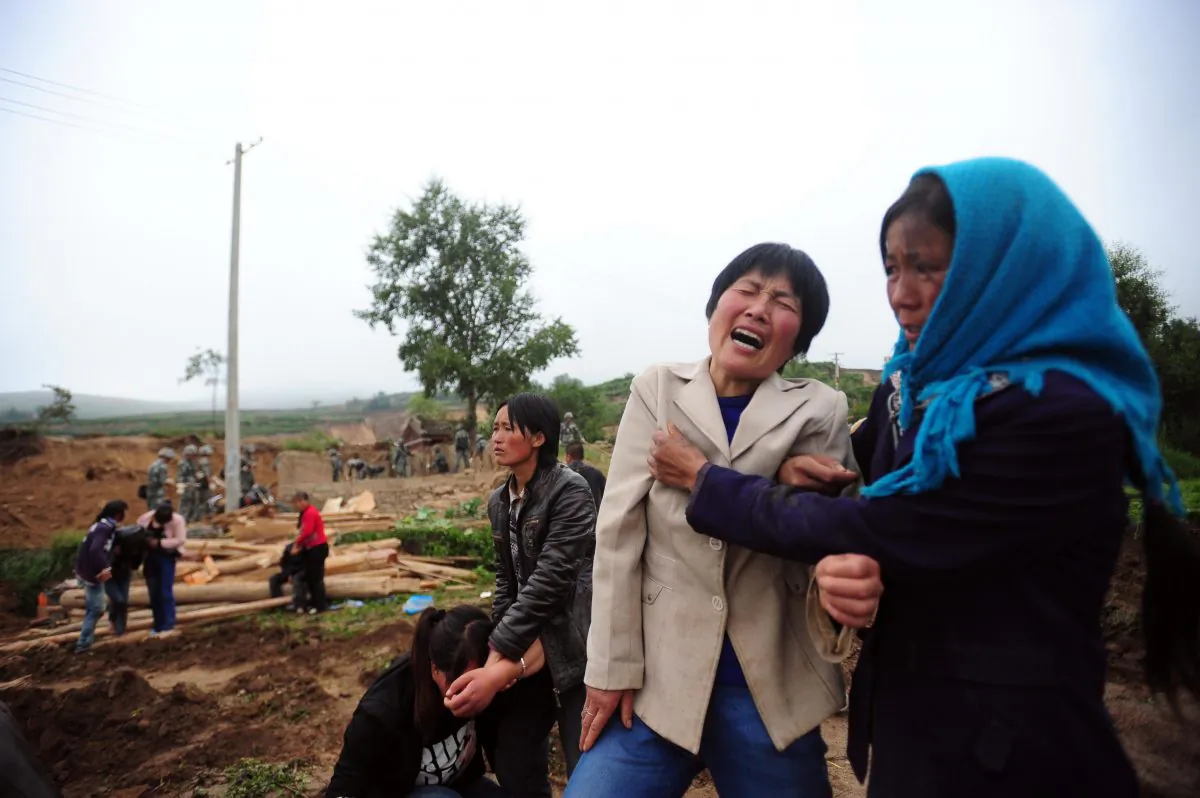 Villagers grieve as preparations are made to bury the deceased from the earthquakes in Yongguang Township, Minxian county in Dingxi, in northwest China's Gansu province, on July 23, 2013. On Tuesday officials said the death toll had risen to 95. (STR/AFP/Getty Images) 