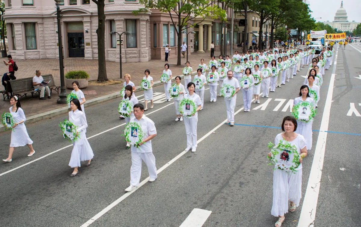 Falun Gong practitioners carry photos of practitioners who have died of torture or abuse in China as a result of the persecution, on July 13, 2012, in Washington, D.C. (Edward Dai/Epoch Times)