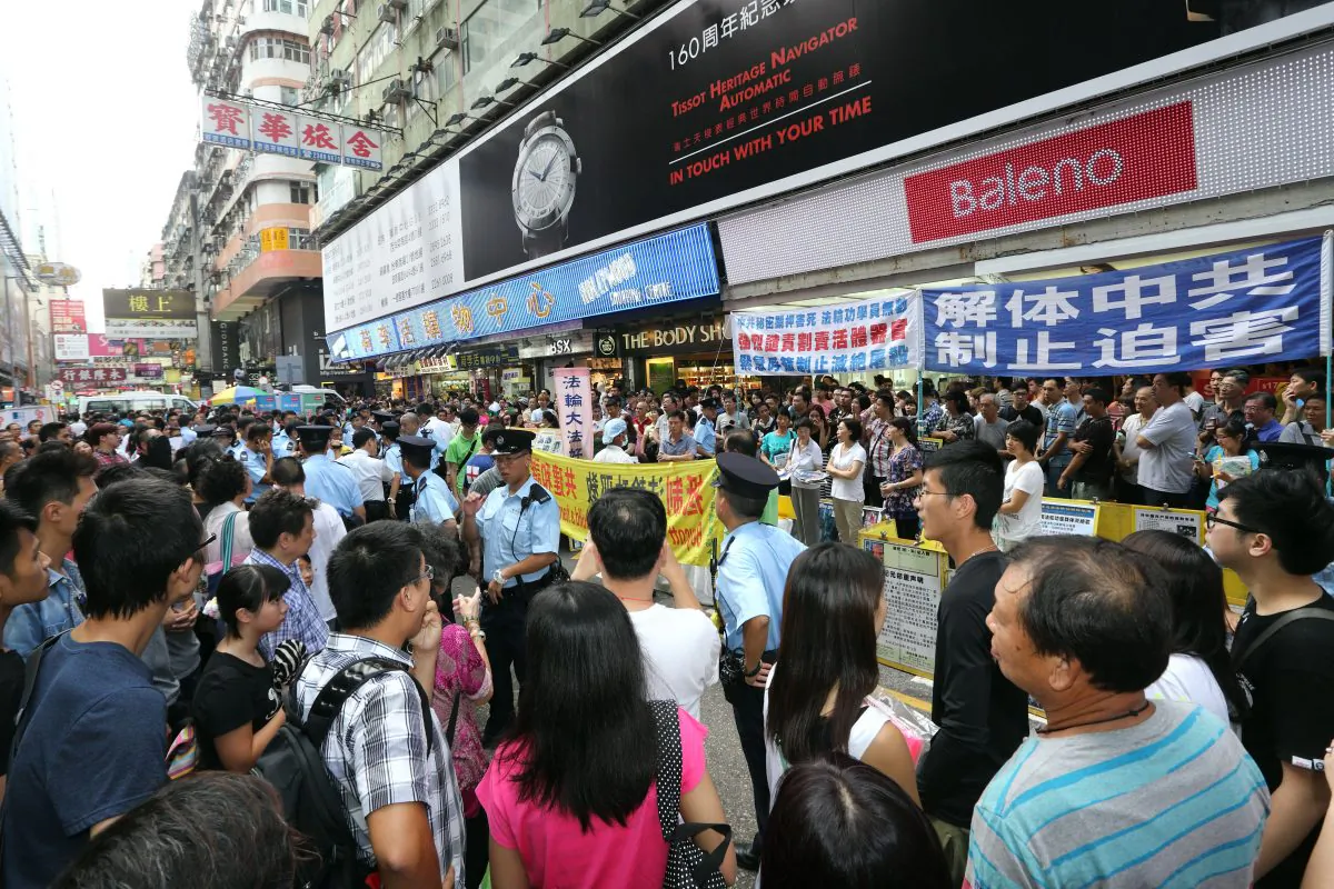 A crowd gathers in front of a Falun Gong information site in Mong Kok District. Members of the Hong Kong Youth Care Association were harassing the practitioners on July 14, prompting bystanders to confront the police for their failure to intervene. (Poon Zoi-syu/Epoch Times)