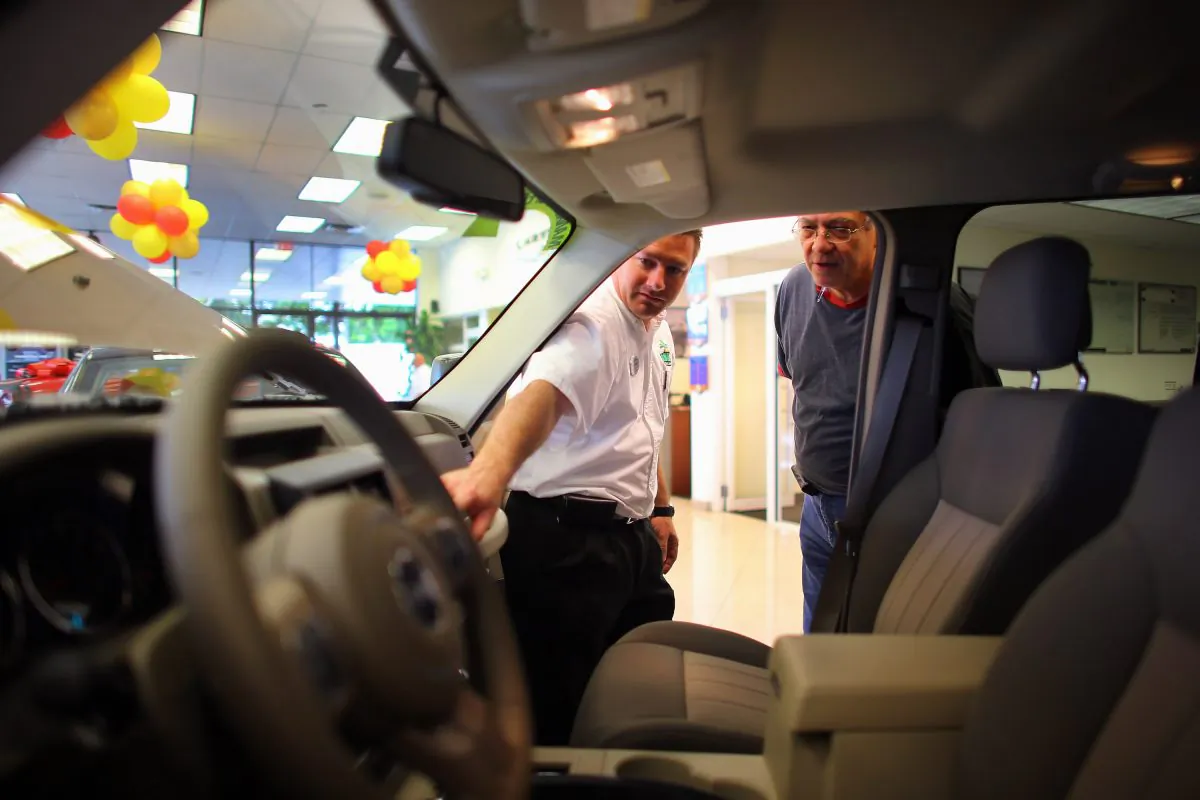 A Chrysler sales consultant (L) shows a Jeep Liberty to a customer at a Chrysler Jeep car dealership in this file photo. Almost all sectors of the Canadian economy made an improved contribution to a jump in retail sales in May. Most notably, vehicle sales were up 4.3 percent. (Joe Raedle/Getty Images)