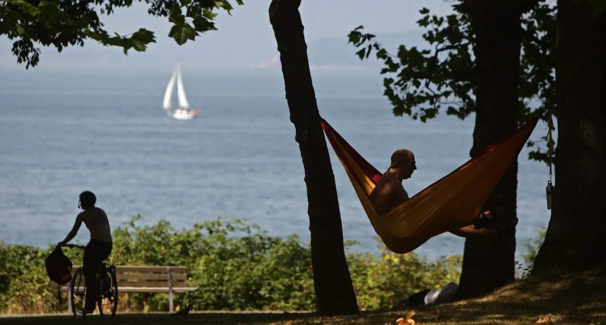 A man relaxes in a hammock as a cyclist rides past, in Kitsilano Beach Park in Vancouver, in a file photo. (The Canadian Press/Darryl Dyck)