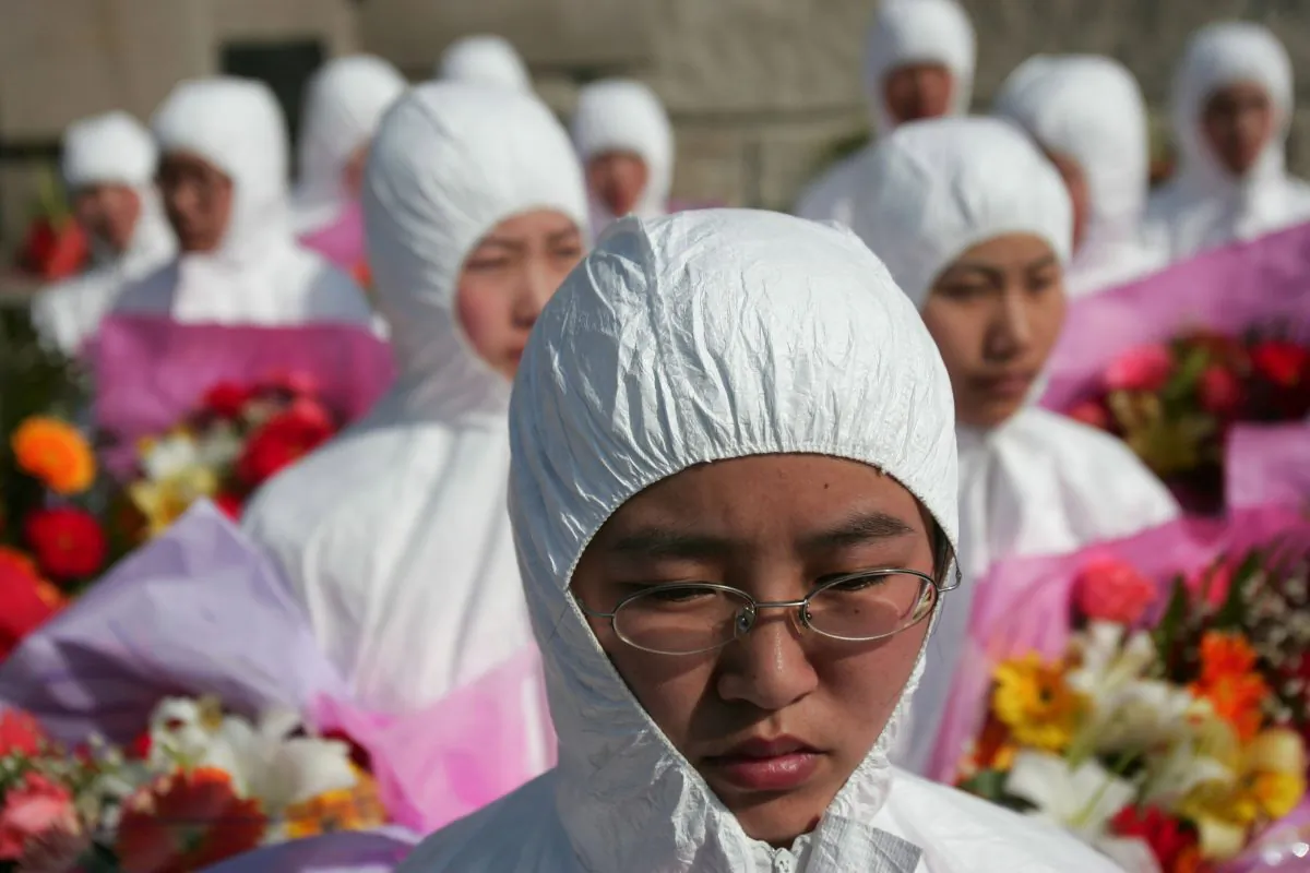 Nurses in protective clothing pay homage to their workmates deceased in the fight against severe acute respiratory syndrome (SARS) in 2003 in a cemetery on April 2 in Beijing, China. According to informed observers, the actual death toll from SARS was far higher than the published official death tolls. (China Photos/Getty Images) 