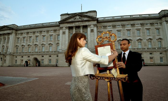 The Queen's Press Secretary Ailsa Anderson with Badar Azim, a footman, places an official document to announce the birth of a baby boy, at 4.24pm to the William and Kate, the Duke and Duchess of Cambridge at St Mary's Hospital, in the forecourt of Buckingham Palace in London Monday July 22, 2013. The child is now third in line to the British throne. (AP Photo/John Stillwell, Pool)