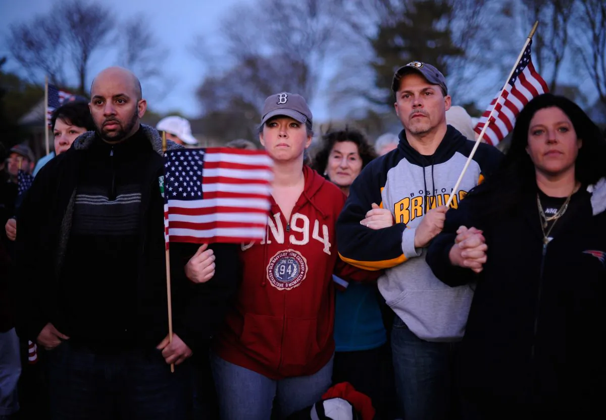 People lock arms and hold hands during a candlelight vigil for victims of the Boston Marathon bombing at Victory Park in Watertown, Mass., on April 20, 2013. Suspected bomber Dzhokhar Tsarnaev will appear in public court for the first time Wednesday, July 10, 2013. (Kevork Djansezian/Getty Images)