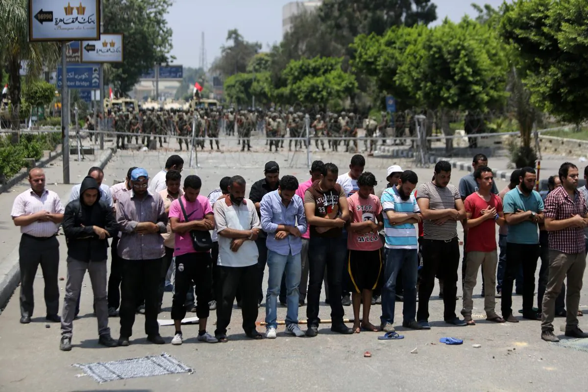 Egyptian supporters of deposed President Mohammed Morsi pray in front of barbed wire fencing that blocks the access to the headquarters of the Republican Guard in Cairo on July 8, 2013. (Mahmud Hams/AFP/Getty Images)