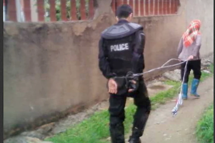 A woman leads a police officer captured after a standoff with authorities over land grabs in Dongwiao Town, Fujian Province, on May 11, 2013. (molihua.org)
