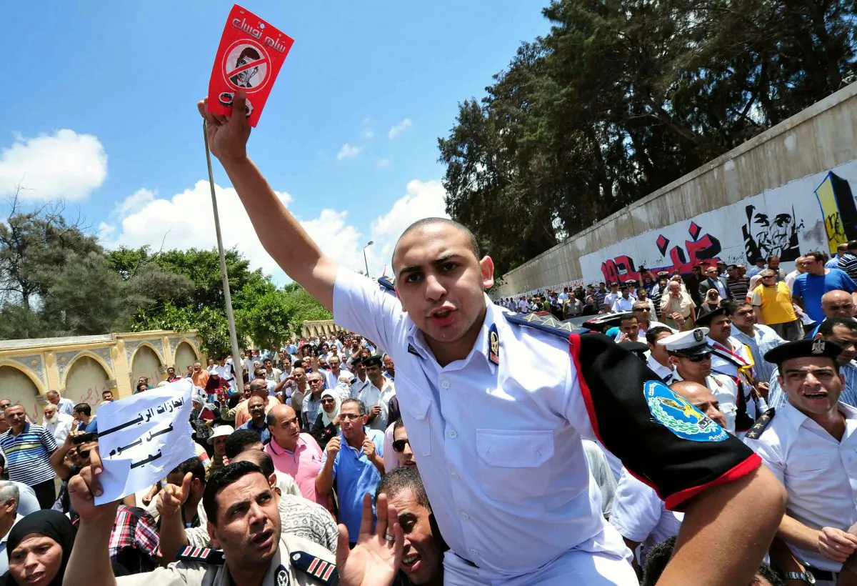 A policeman holds up a poster against Egypt's now-ousted President Mohammed Morsi during an anti-government demonstration on July 1, 2013, following the funeral procession of Egyptian police officer Colonel Mohammed Hani, who was killed by unknown gunmen in the Sinai town of El-Arish, Egypt. (STR/AFP/Getty Images)