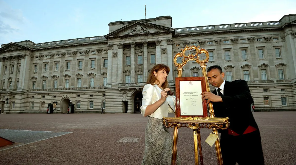 The Queen's Press Secretary Ailsa Anderson, with Badar Azim, a footman, places an official document to announce the birth of a baby boy, at 4.24pm to the Duke and Duchess of Cambridge at St Mary's Hospital, in the forecourt of Buckingham Palace in London Monday July 22, 2013. The child is now third in line to the British throne. (AP Photo/John Stillwell, Pool)