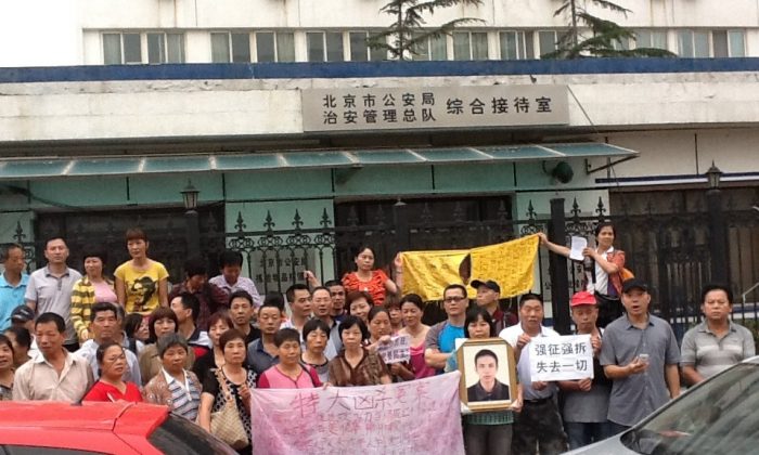 Petitioners from across China stand outside a building affiliated with the Beijing Public Security Bureau on July 1, the 92nd anniversary of the founding of the Chinese Communist Party. They held signs and shouted out slogans like "Down with corrupt officials." (Human Rights Campaign in China)