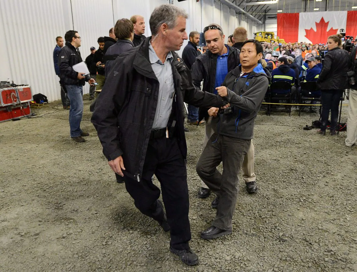 Li Xue Jiang of the People's Daily, a newspaper owned and controlled by the Chinese Communist Party, is hauled to the back of the room by RCMP after making an aggressive attempt to question Prime Minister Stephen Harper at Xstrata Nickel's Raglan Mine in northern Quebec on Aug. 23. (The Canadian Press/Sean Kilpatrick)