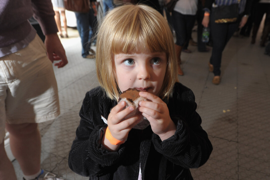 A young girl indulges in a bite to eat during an even in New York in this file photo. Recent studies show that involving your child in the cooking process and having it eat a lot of raw produce will benefit it over the long term. ((Michael Loccisano/Getty Images for City Harvest)