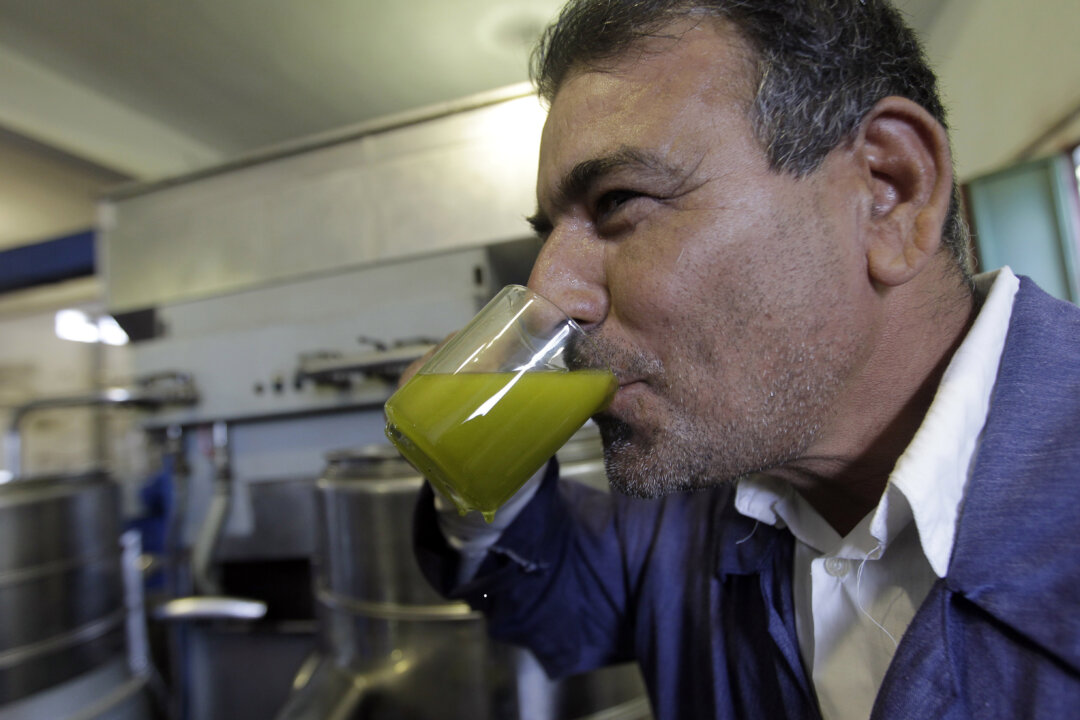 A Libyan man tastes freshly pressed olive oil to check the quality at an olive press in the town of Zliten, east of the capital Tripoli, on Nov. 11, 2011. (Joseph Eid/AFP/Getty Images)