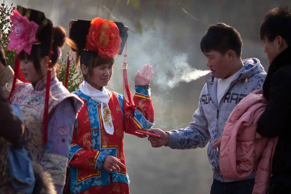 A tourist dressed in Qing dynasty style clothing waves away cigarette smoke in Beihai park in Beijing on Dec. 4, 2012. Efforts to curb smoking in China have not been much of a success owing to widespread ignorance of the laws and lack of enforcement. (Ed Jones/AFP/Getty Images)