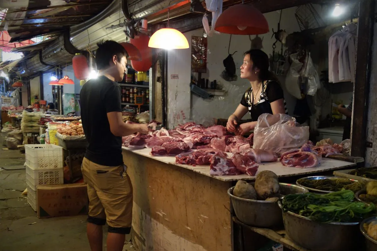 In this picture taken on June 1, 2013 a man (R) browses meat at a shop selling pork in Beijing. An abattoir in Beijing was recently found to have been selling diseased meet to high schools for over a year. (Wang Zhao/AFP/Getty Images)