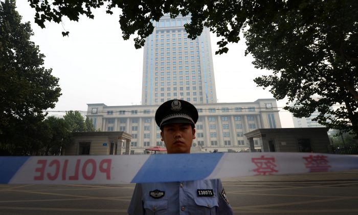 A police officer stands guard at the Intermediate People's Court in Jinan, Shandong Province, China, on Aug. 24, 2013. (Mark Ralston/AFP/Getty Images)
