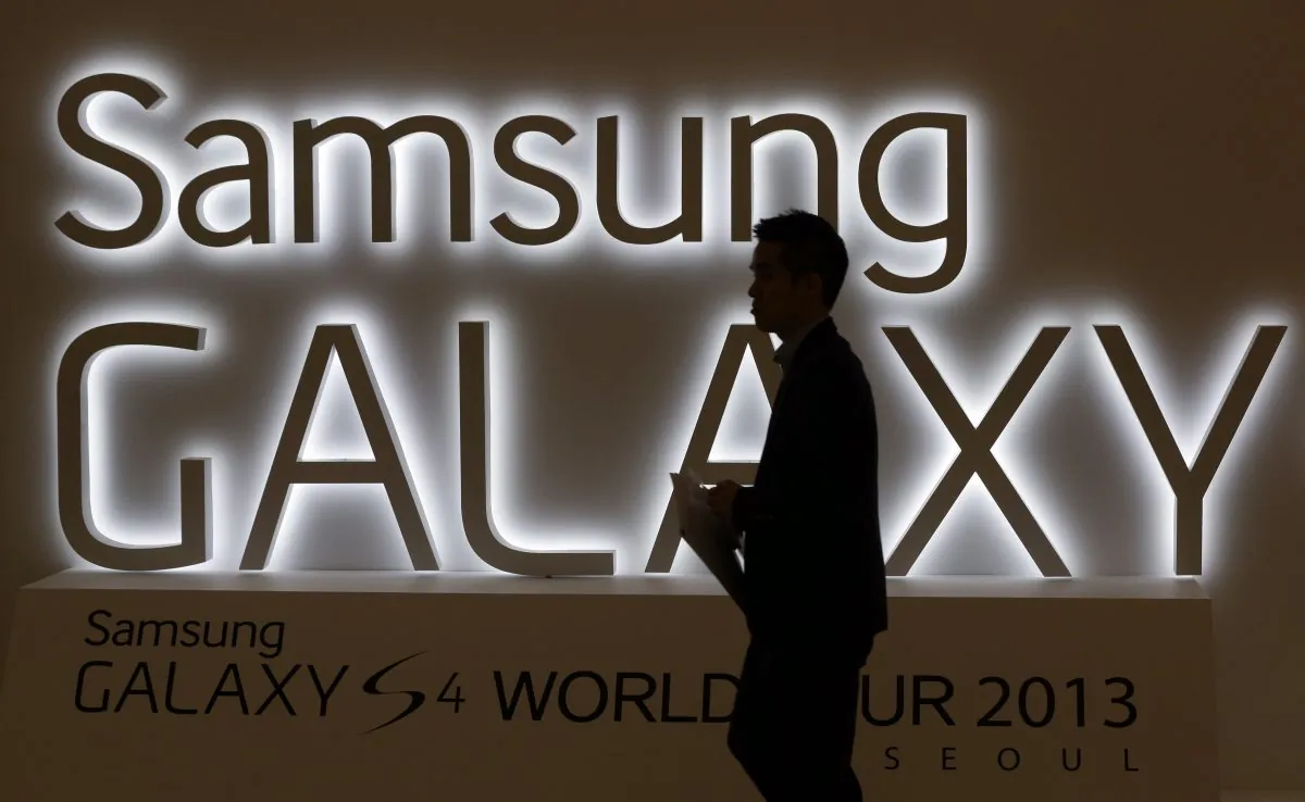 In this photo taken on April 25, 2013, a man walks by a logo of Samsung Electronics Co.'s latest smartphone Galaxy S4 during its unveiling ceremony in Seoul, South Korea. Samsung Electronics Co. has applied for U.S. and South Korean trademarks for a watch that connects to the Internet in the latest sign that consumer technology companies see wearable devices as the future of their business. (AP Photo/Lee Jin-man)
