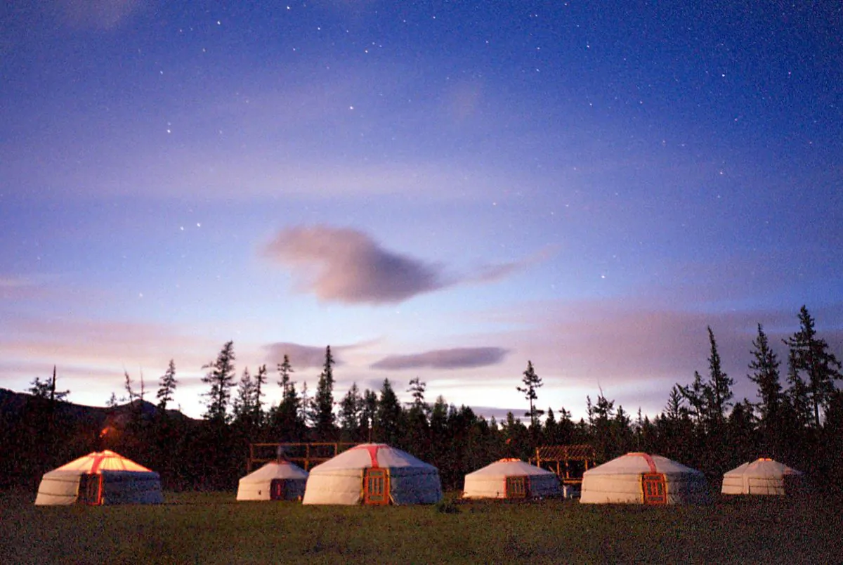 The sun goes down behind a mountain ridge as tourists light the furnaces in their Gers, or traditional Mongolian tents, on northern Mongolia's alpine Khovsgol Lake, in this file photo. (Stephen Shaver/AFP/Getty Images)