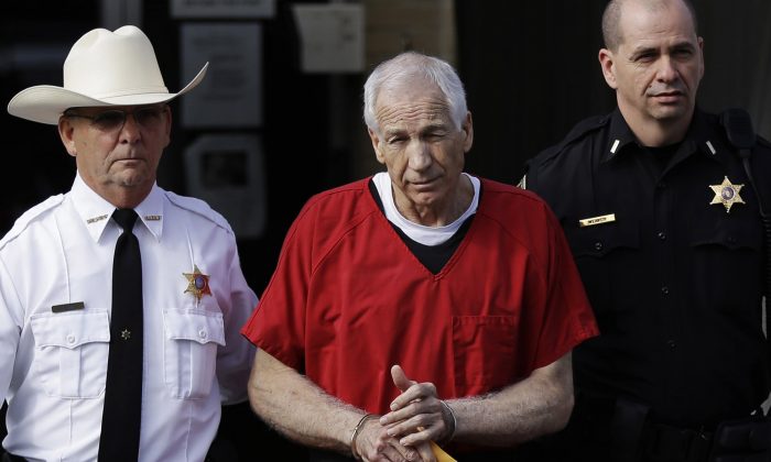 Former Penn State University assistant football coach Jerry Sandusky (C) is taken from the Centre County Courthouse Oct. 9, 2012. (AP Photo/Matt Rourke, File)