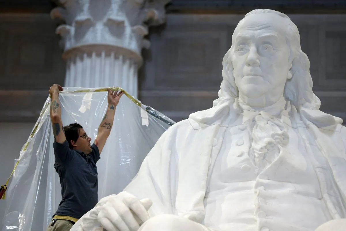 A workman wraps a statue of Benjamin Franklin in aprotective cover in preparation for upcoming construction at the The Franklin Institute in Philadelphia on Aug. 20, 2013. (AP Photo/Matt Rourke)