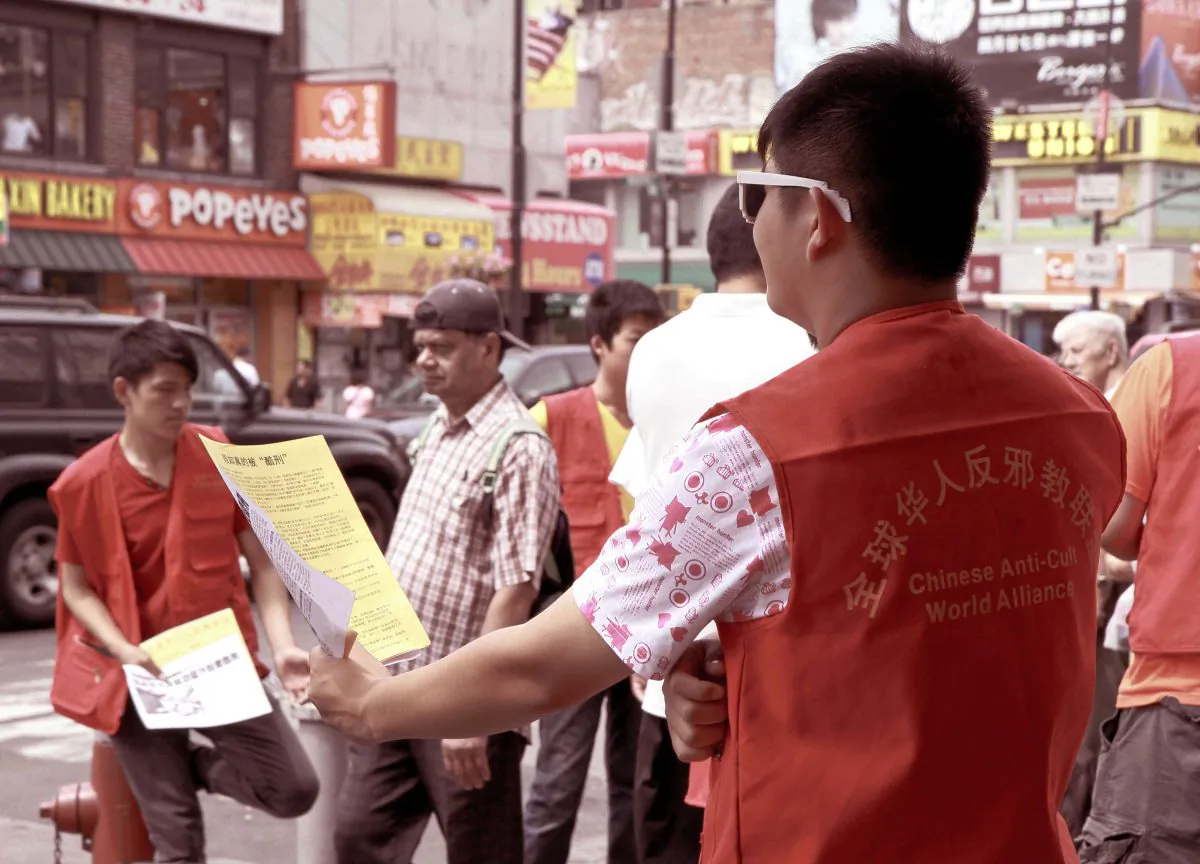 A group of 16-year-old youths try to hand the CCP's hate materials to passersby on Main Street in Flushing, Saturday, Aug. 10. (Milene Fernandez/Epoch Times)
