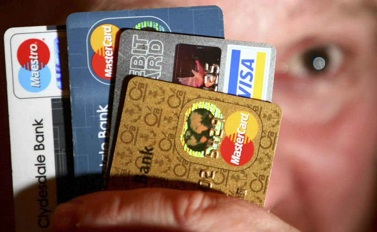 In this photo illustration a man holds up credit and debit cards. Many Americans have a wallet full of credit cars, but they have been paying them off more quickly. (Jeff J Mitchell/Getty Images)