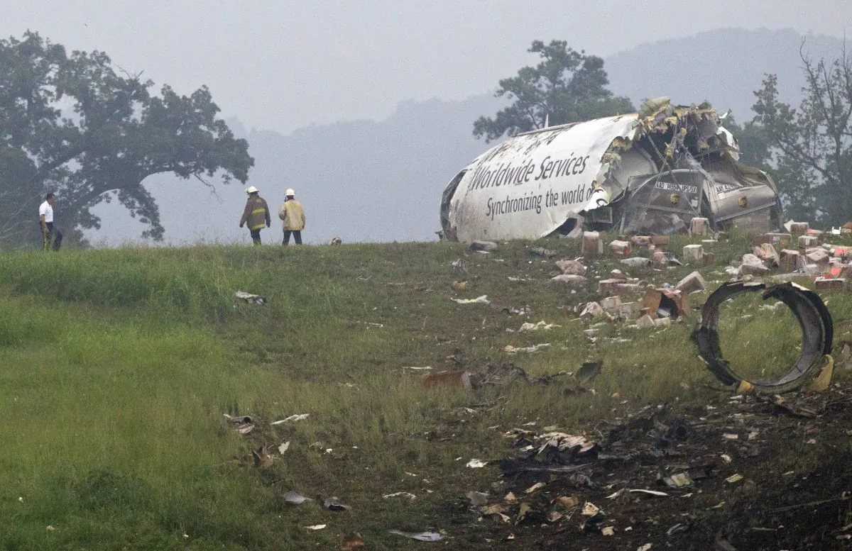 Fire crews investigate where a UPS cargo plane lies on a hill at Birmingham-Shuttlesworth International Airport, in Birmingham, Ala. after crashing on approach on Wednesday, Aug. 14, 2013. (AP Photo/Butch Dill)